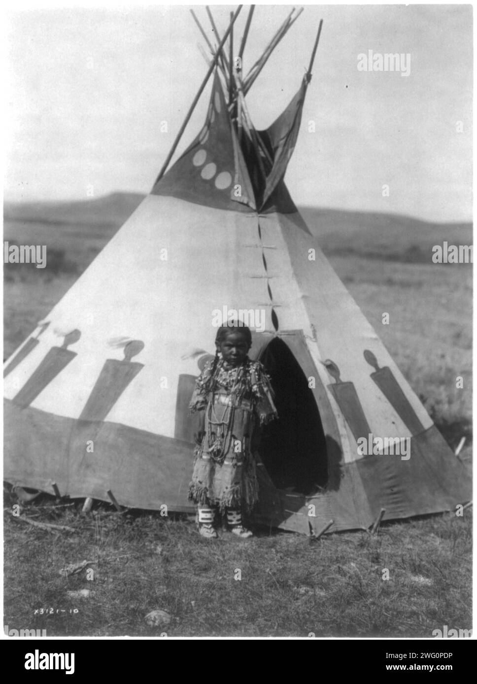 A child's lodge, c1910. Piegan girl standing outside small tipi. Stock Photo