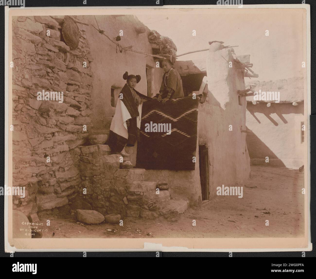 Tewa girls, c1900. Two Tewa girls standing outside pueblo building ...
