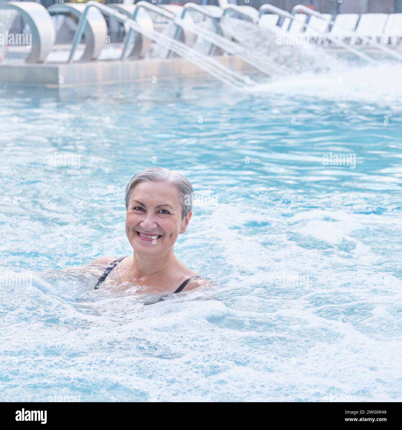 Happy smiling senior caucasian woman in outdoor thermal swimming pool ...