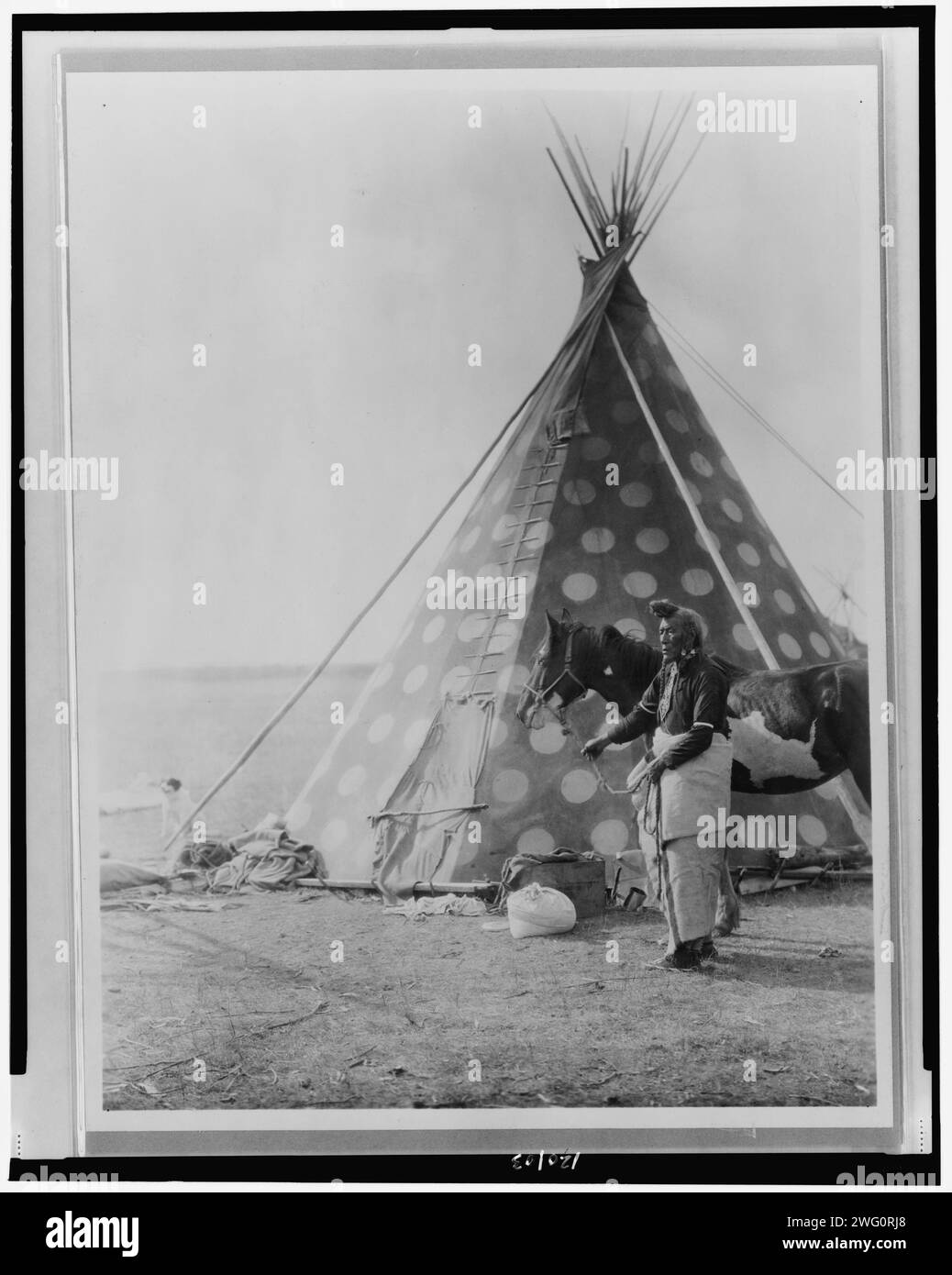 A Blackfoot tepee, c1927. Blackfoot Indian, (Bear Bull?) holding horse outside tipi. Stock Photo