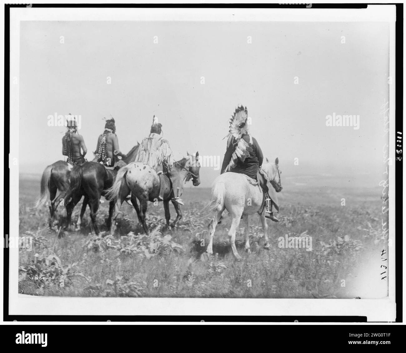 The chief and his staff, Apsaroke Indians, c1905. Rear view of four Apsaroke Indians on horseback Stock Photo