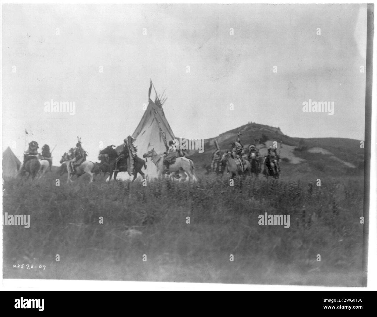 Start of war party, c1907. Several Dakota men on horseback riding in a