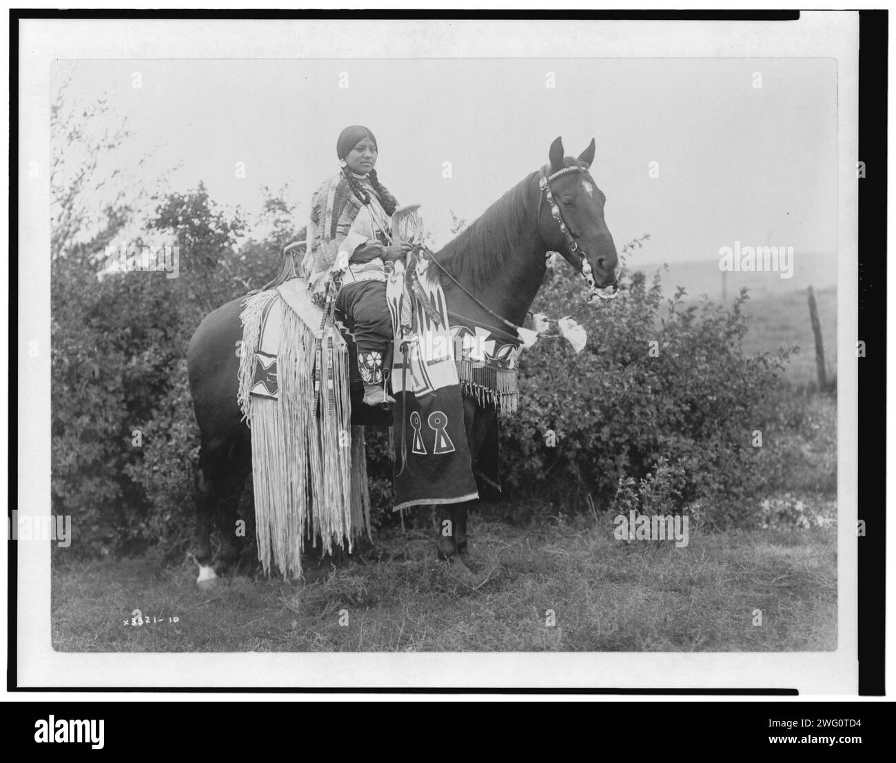 Holiday trappings, c1910. Cayuse woman on horseback, wearing beaded buckskin dress; horse has long fringe and beaded trappings, Oregon. Stock Photo