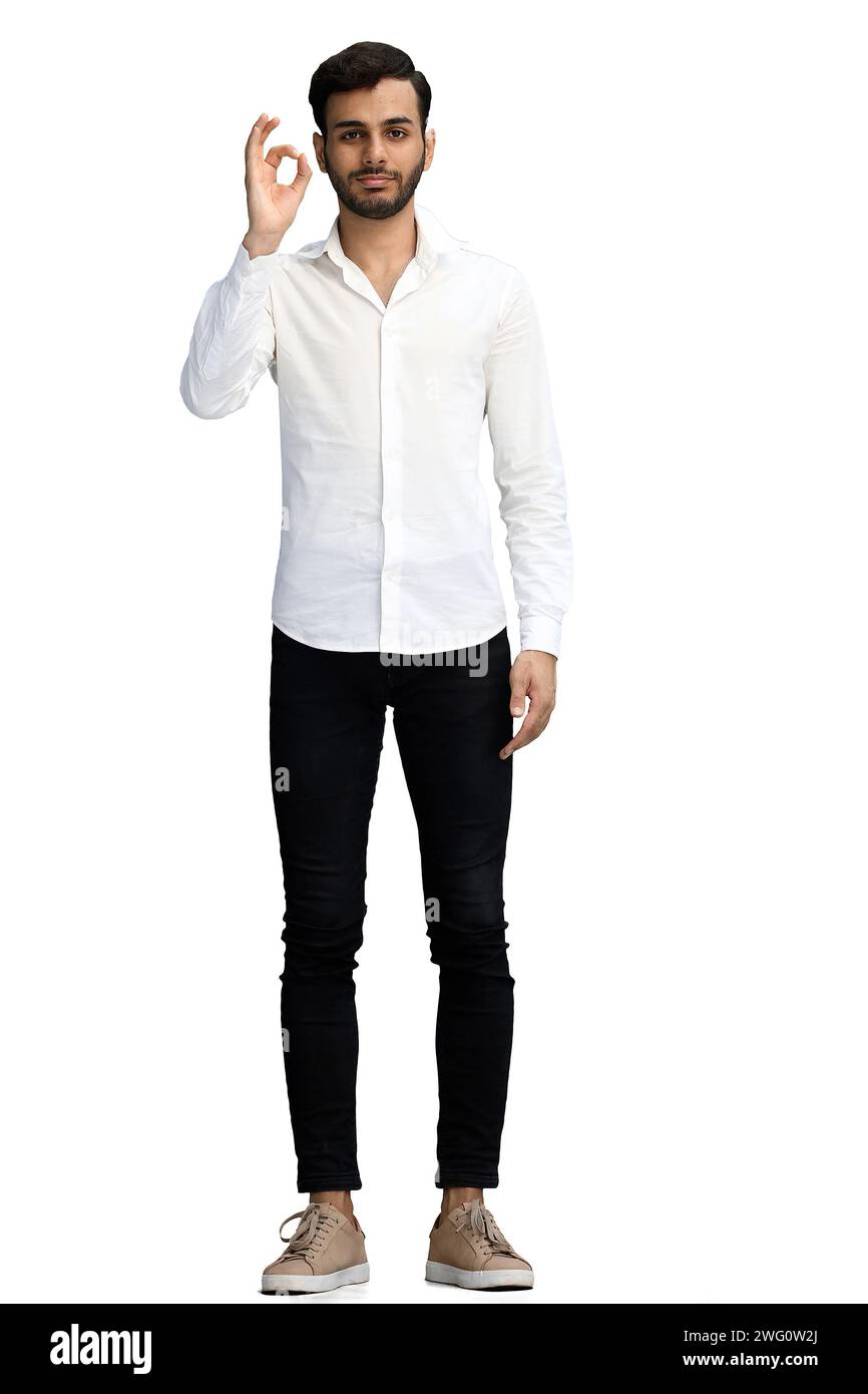 A young man on a white background shows an ok sign in full growth Stock ...