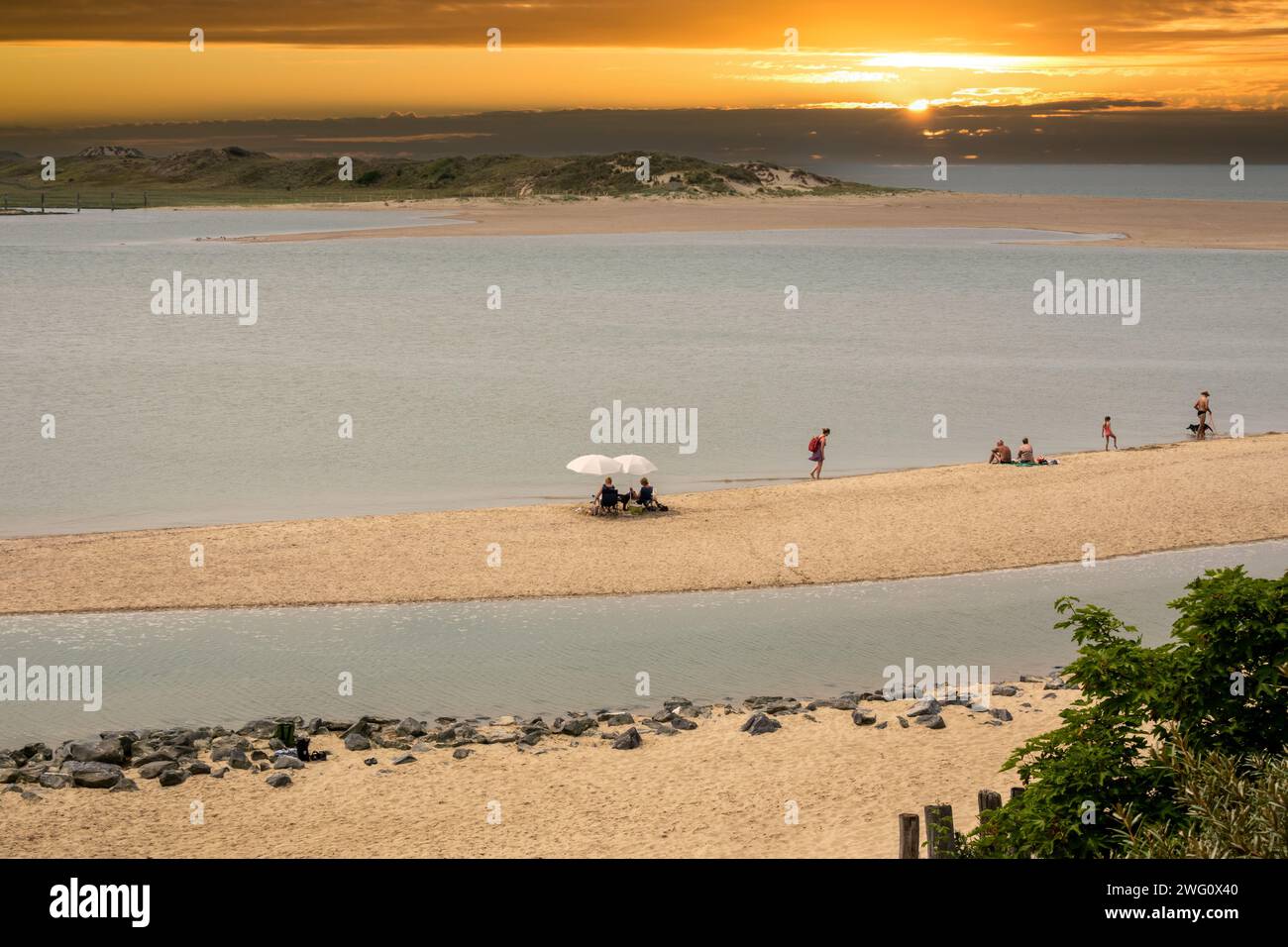 People on beach of tidal inlet of The Zwin nature reserve at North Sea coast at sunset, at border between Belgium and the Netherlands Stock Photo