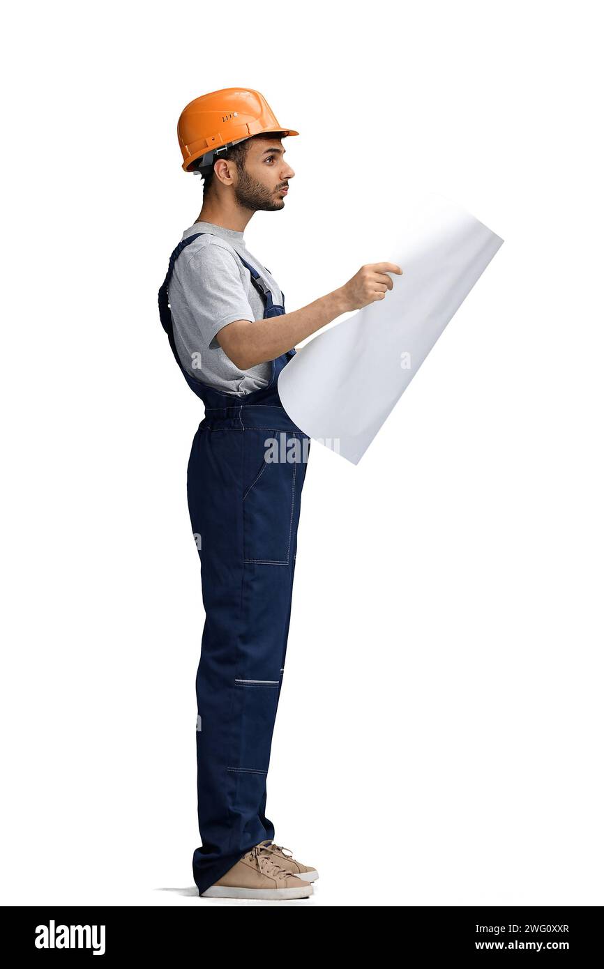 A builder male on a white background look at the blueprint, in profile ...