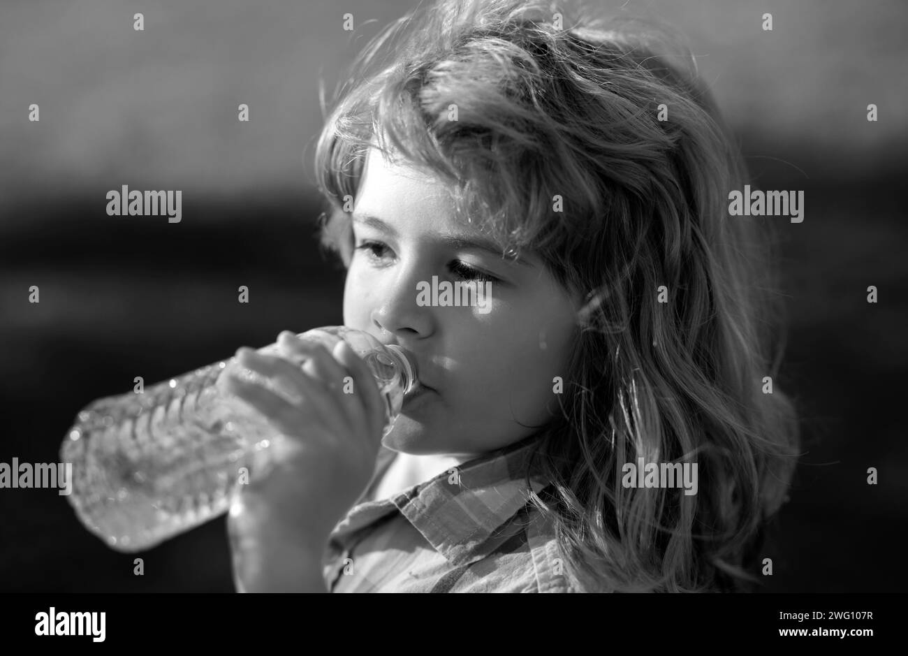 Close up portrait of kid boy drinking water from pet bottle outdoor Stock Photo