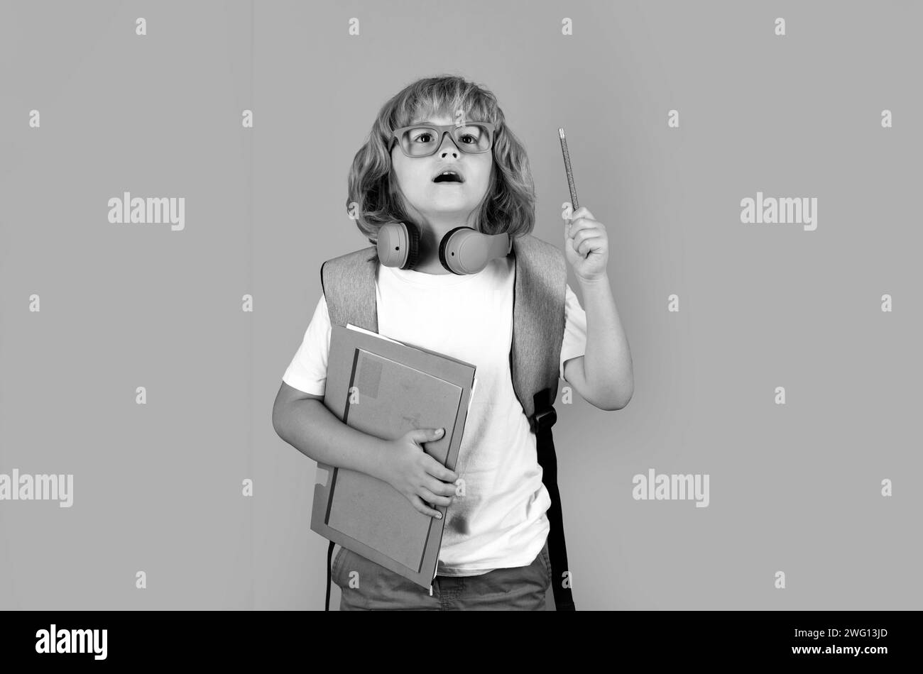 Portrait of pupil student hold book on grey isolated studio background. School and education concept. Back to school. Surprised amazed emotions of sch Stock Photo