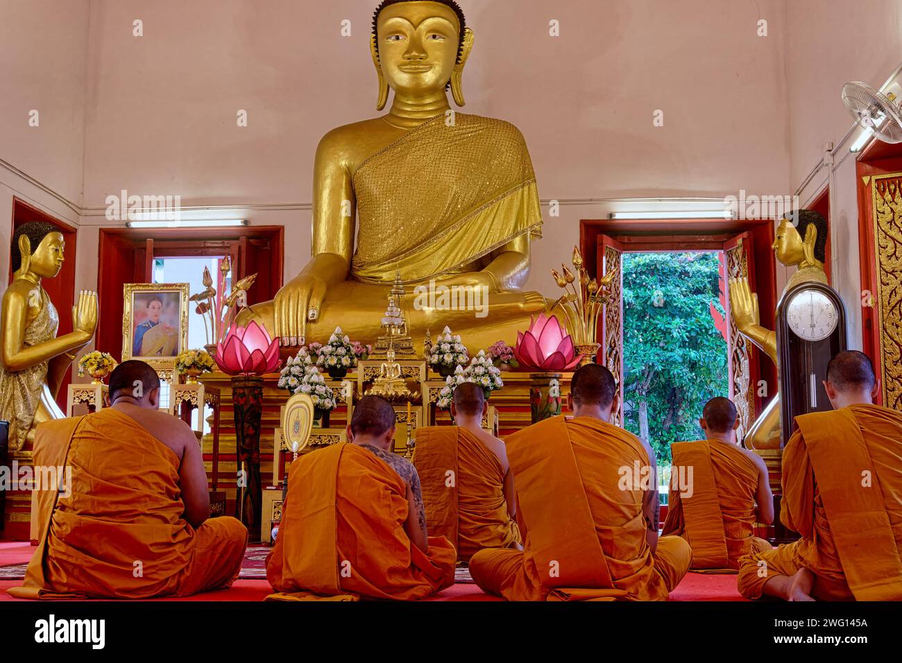 Thai Buddhist monks sitting in front of a Buddha statue chanting Pali prayers; at Wat Mongkol