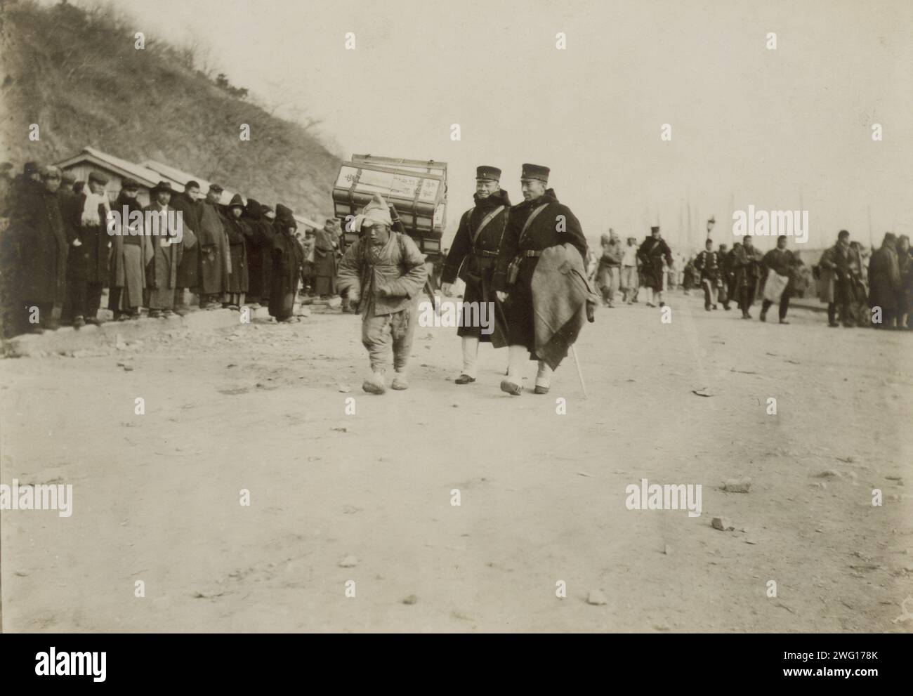 A Korean coolie carrying medical supplies from shore to hospital at