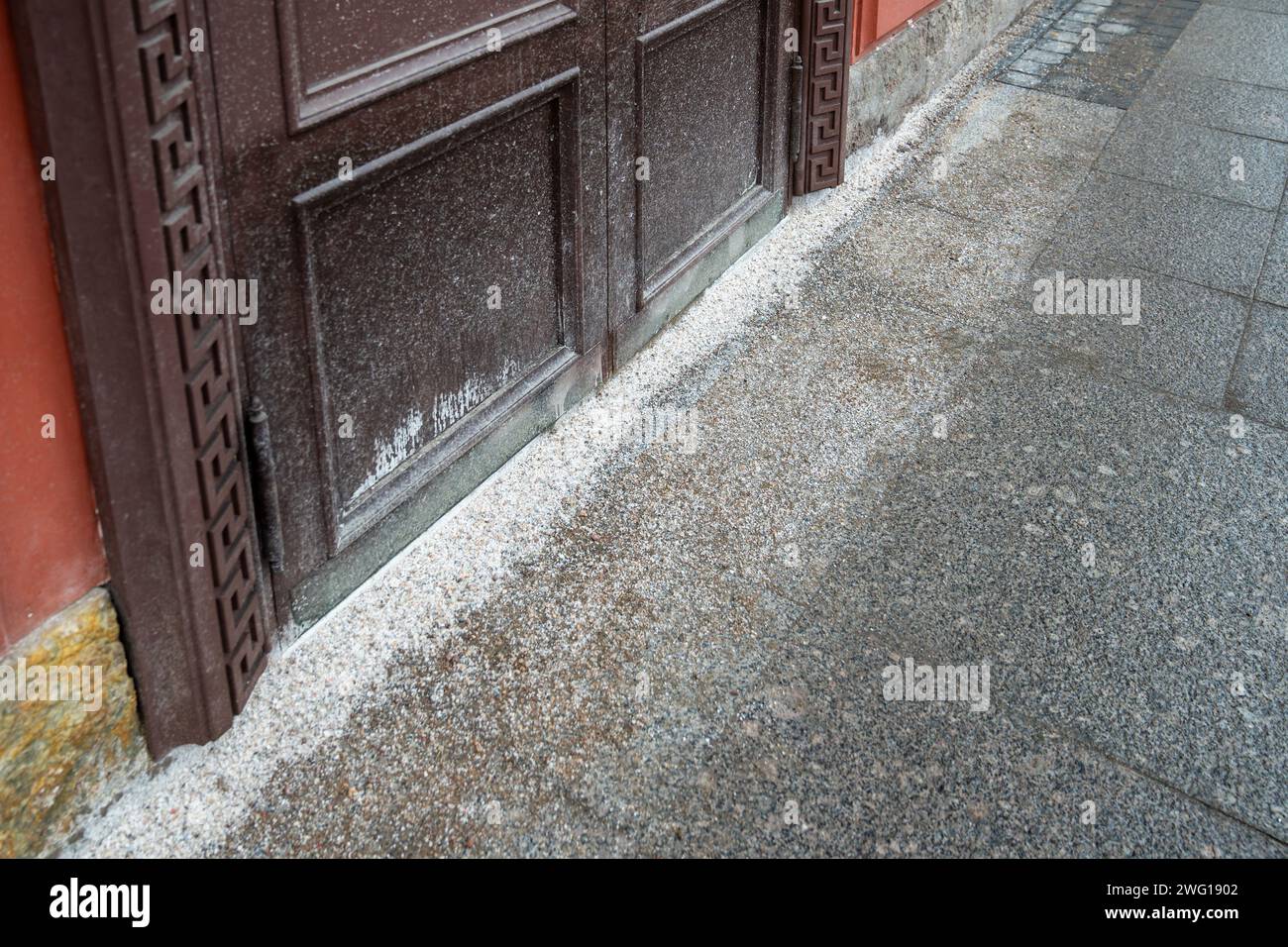 Thaw salt covering sidewalk near building entrance for deicing, surface frost removal in winter Stock Photo