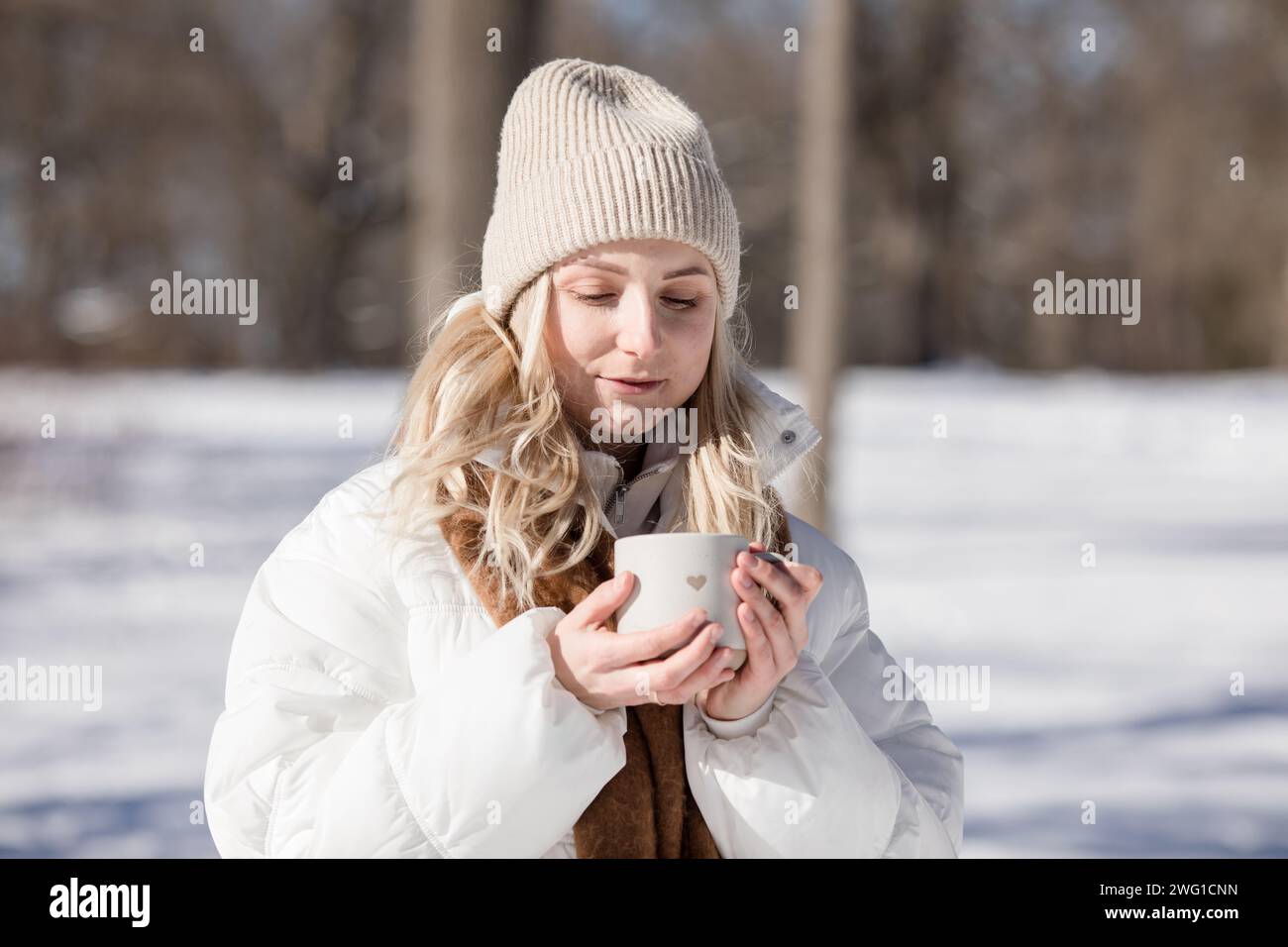 Woman  drinking cup of hot tea or coffee outdoors in sunlight in cold winter day. Valentine day Stock Photo