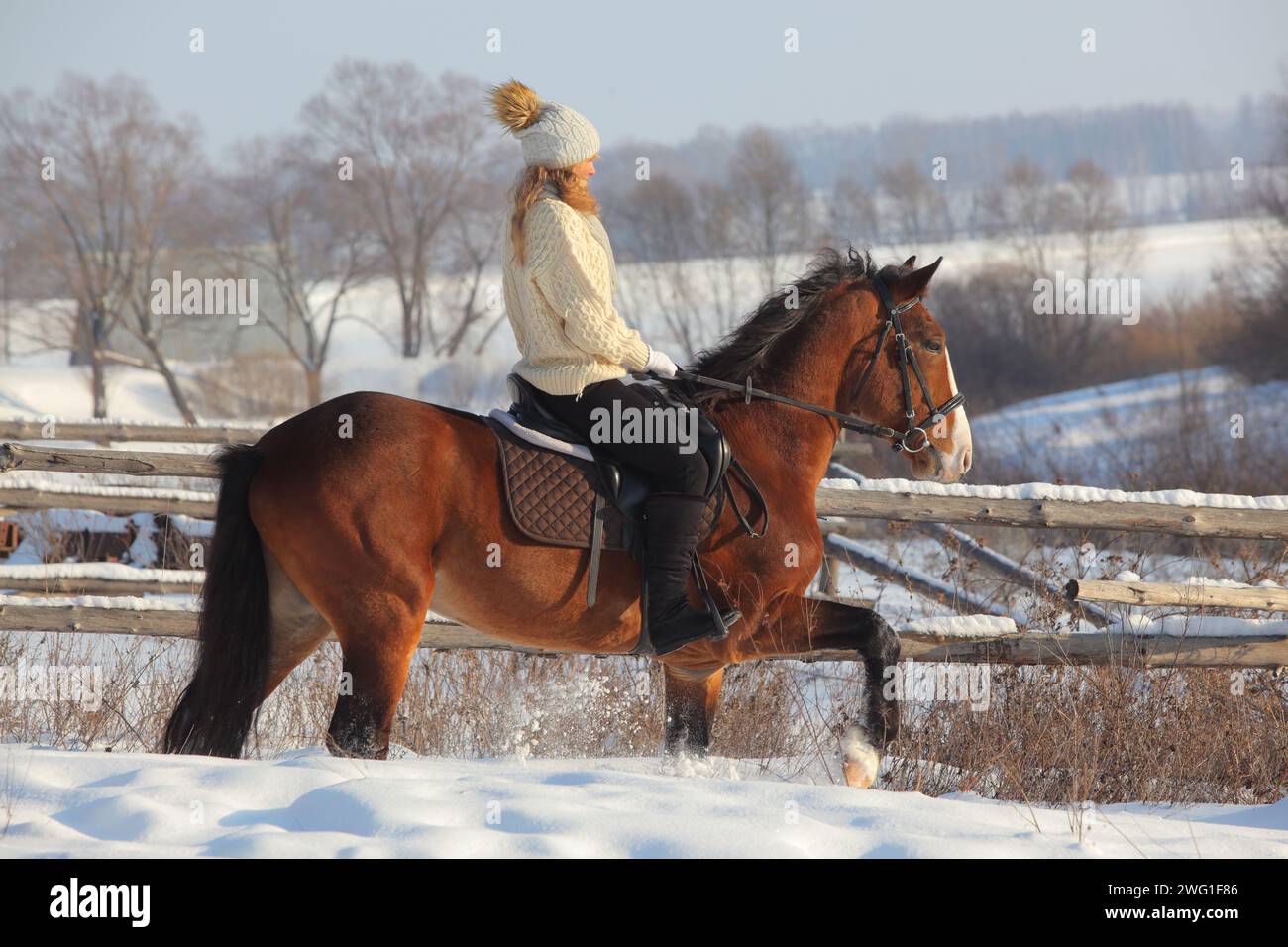 Girl galloping on horse in snowing winter ranch Stock Photo
