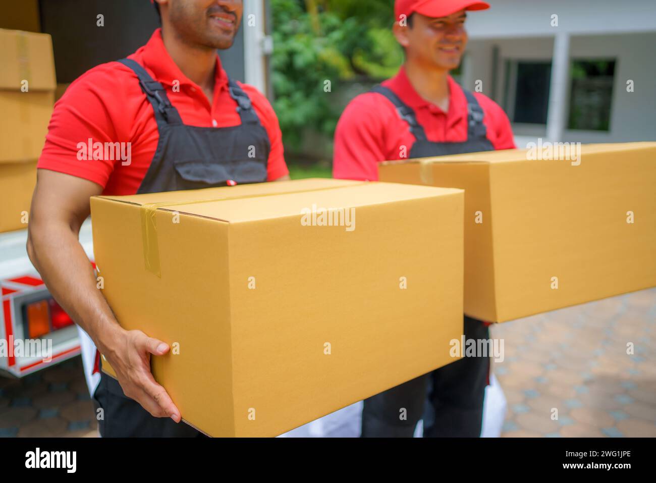 Two male delivery professionals as they hold parcels, ready to deliver them to customers at their doorstep Stock Photo