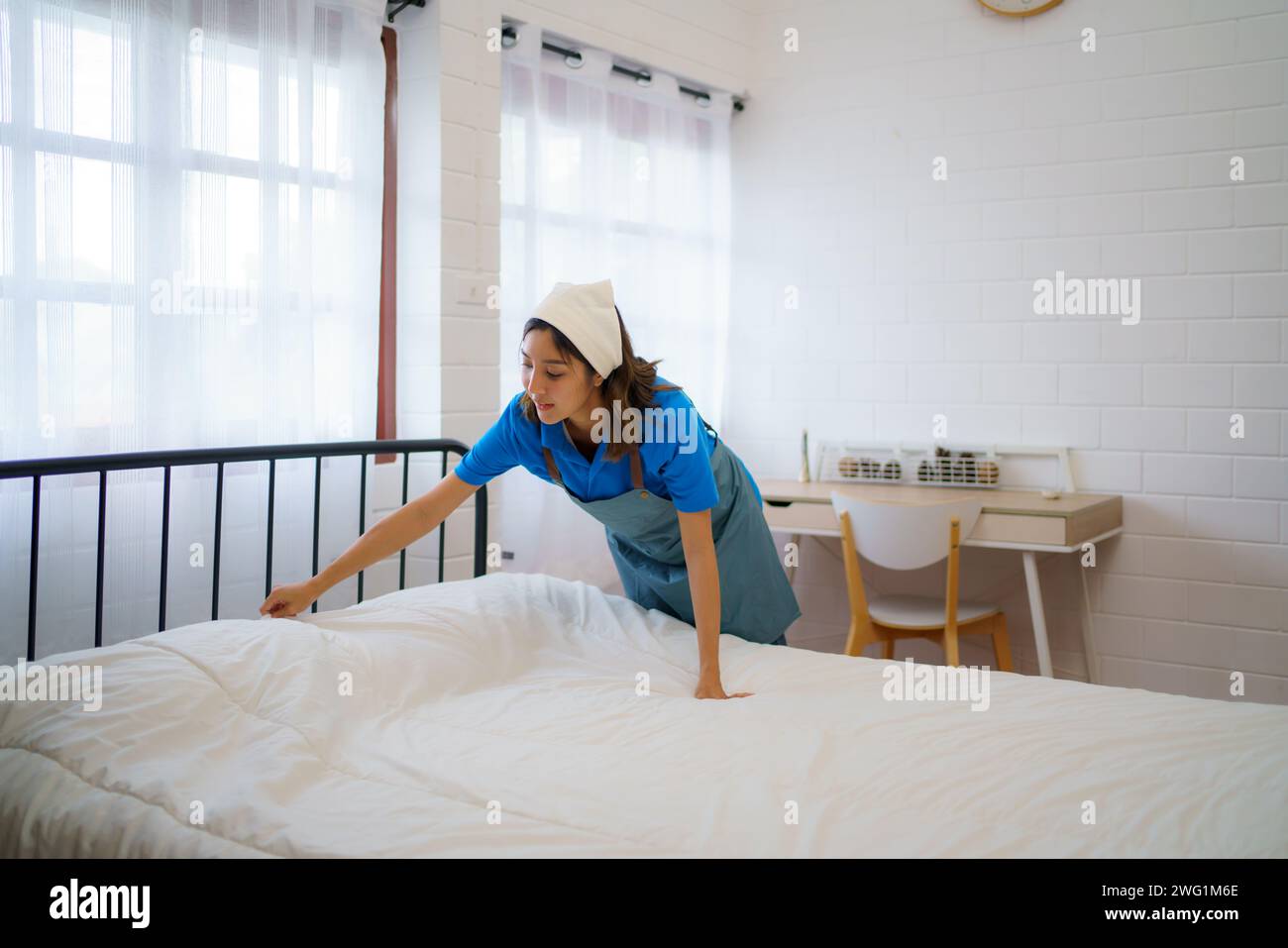 Housekeeper expertly arranges and smooths the bedding in a bedroom professionalism and dedication of the housekeeping team Stock Photo