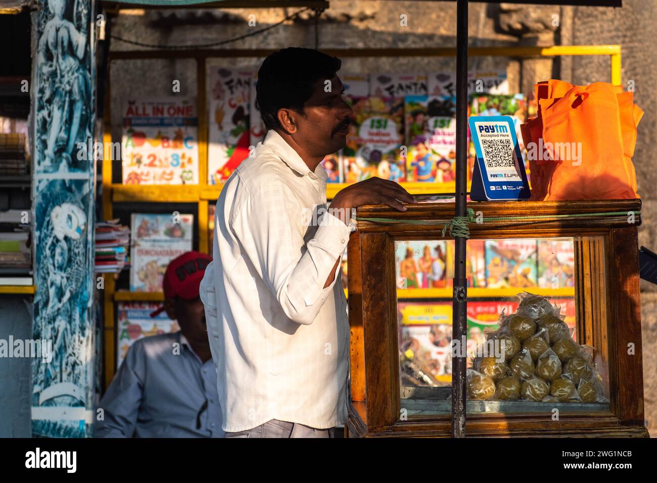 Belur, Karnataka, India - January 9 2023: An Indian street vendor with a paytm upi QR code for payments at his colorful snack stall. Stock Photo