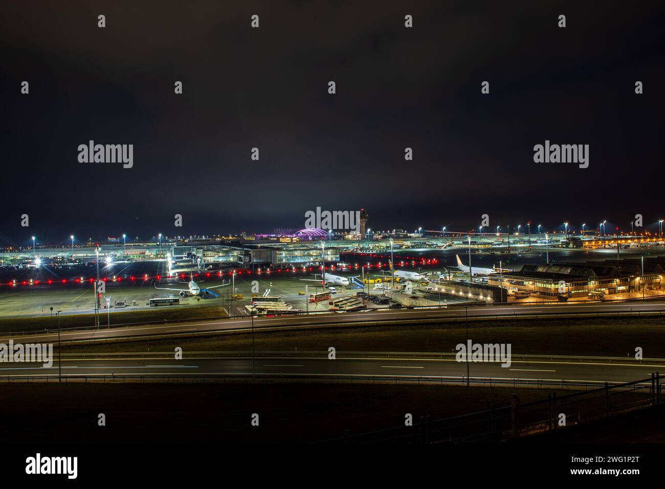 A jet landing at Munich airport at daybreak leaves a light streak. Stock Photo