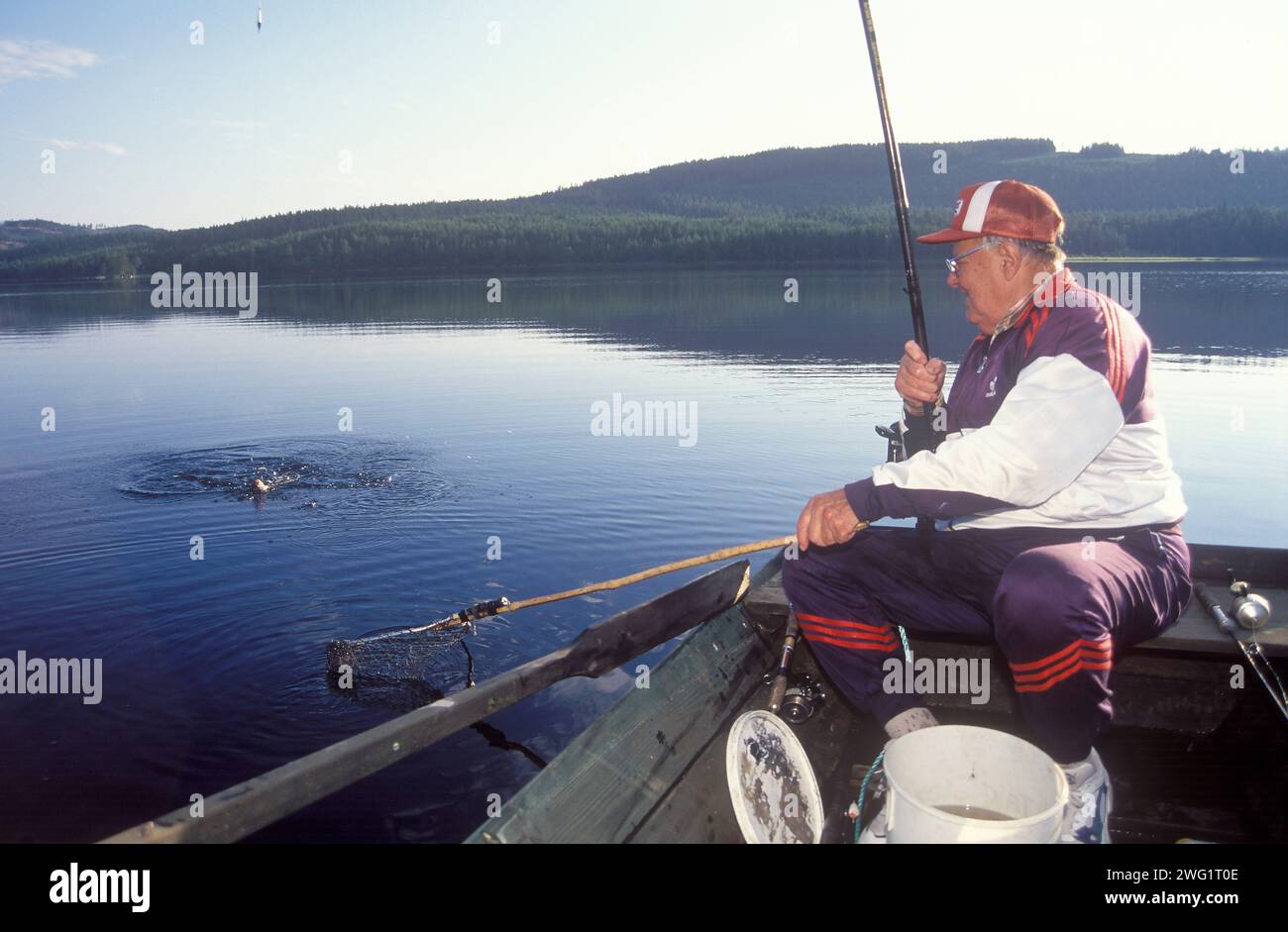 Old man fishing from rowing boat Stock Photo