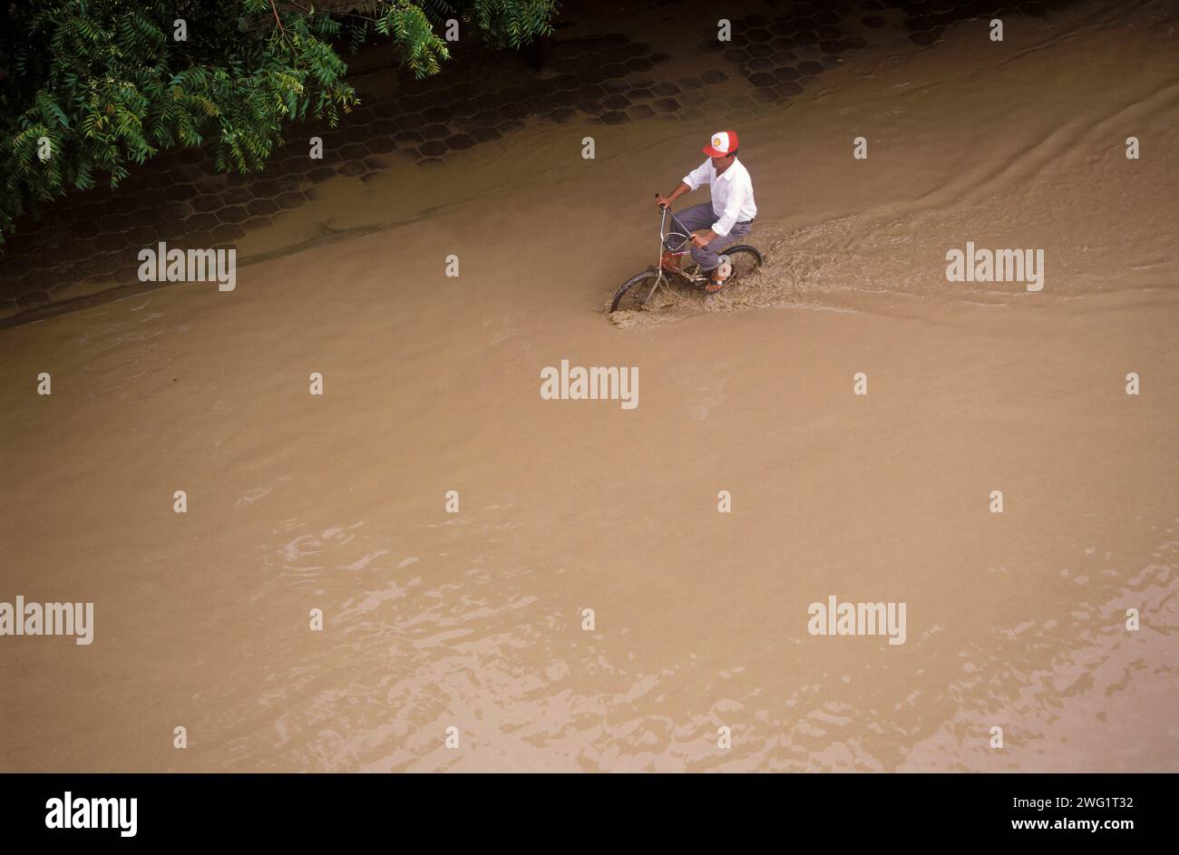 Man cycling on flooded street Stock Photo