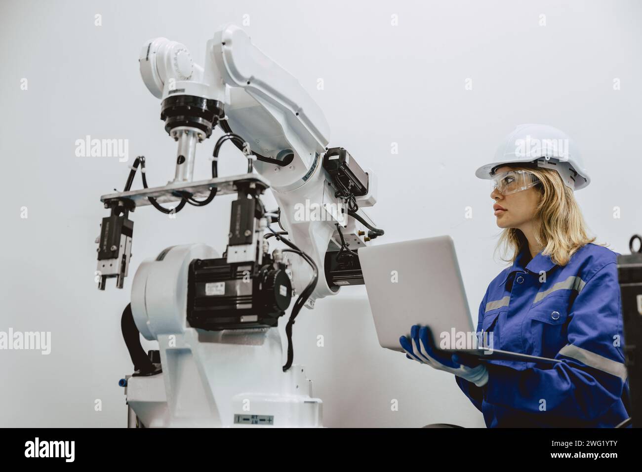 Engineer women university student learn control operate and program industry robot arm with laptop computer in robotics engineers lab classroom in pol Stock Photo