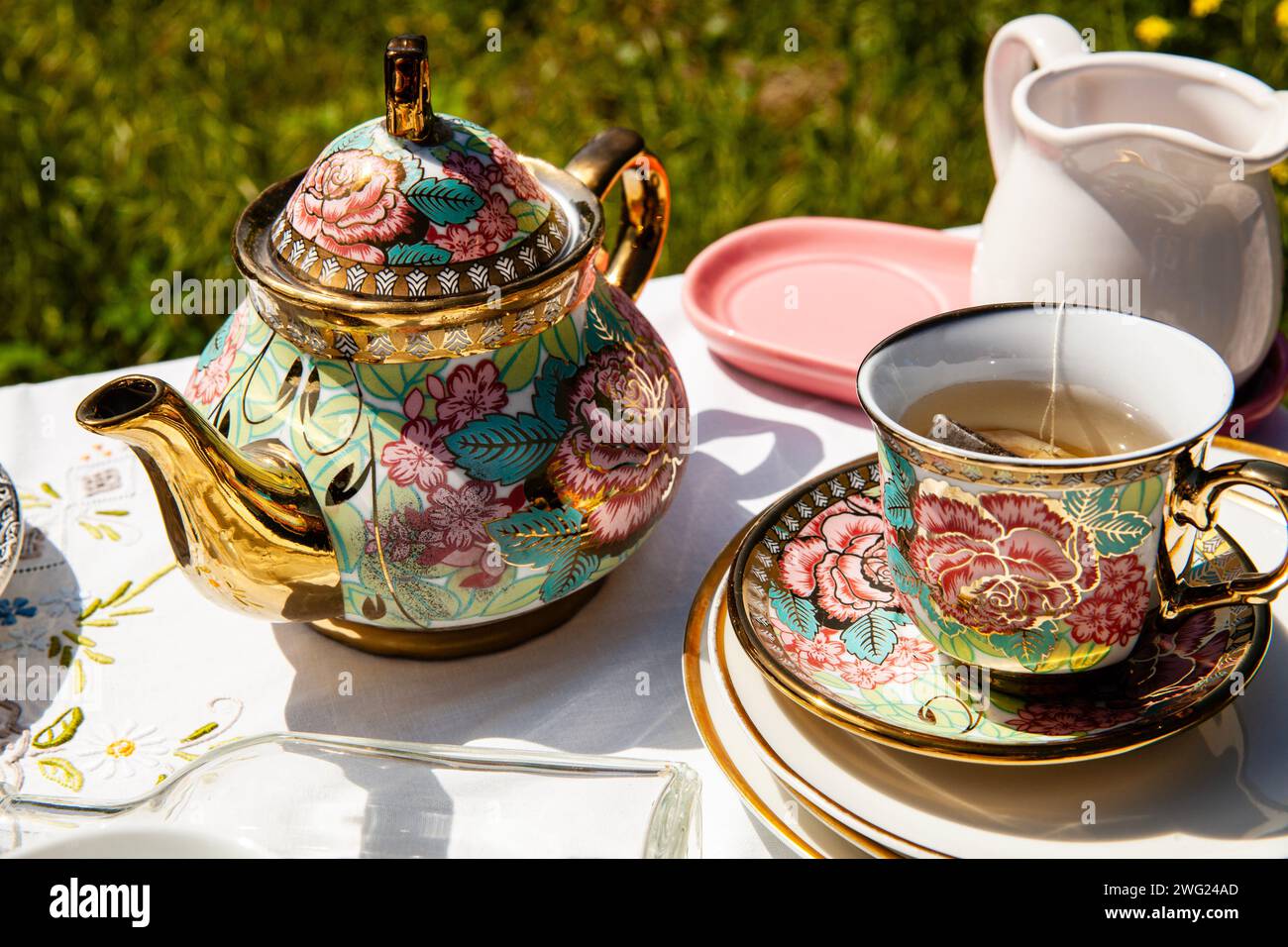A luxurious tea set with a golden floral teapot and cup, basking in the