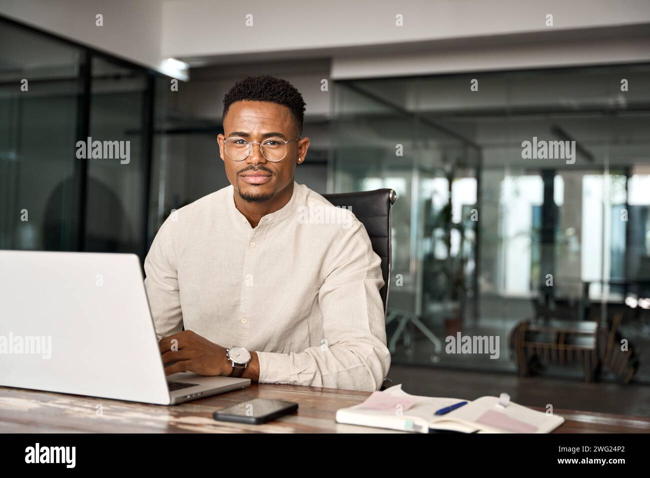 Confident professional African business man looking at camera using computer. Stock Photo