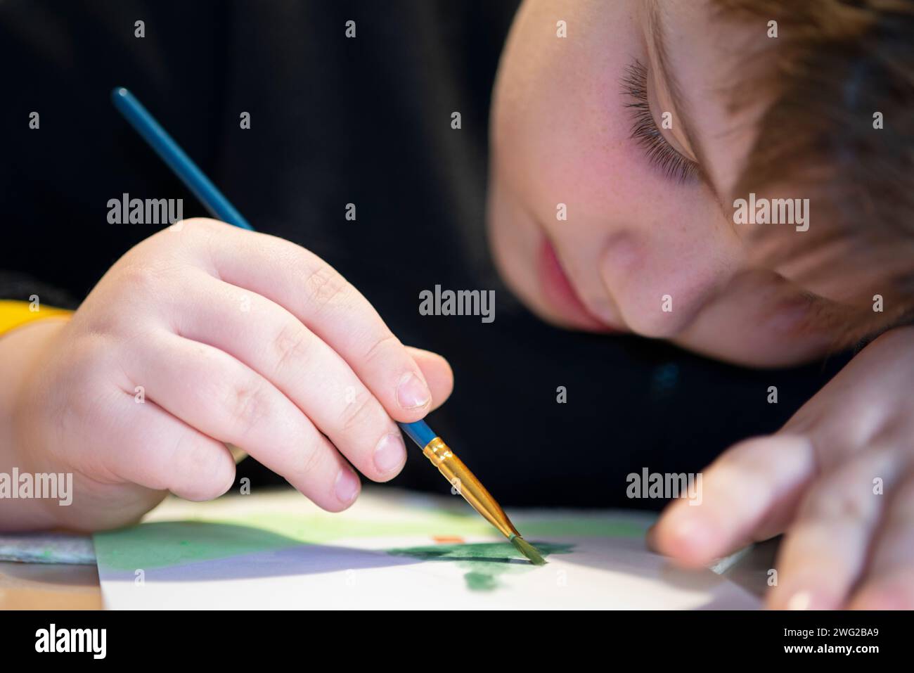 Boy Learns to Paint with a Brush on Paper Stock Photo