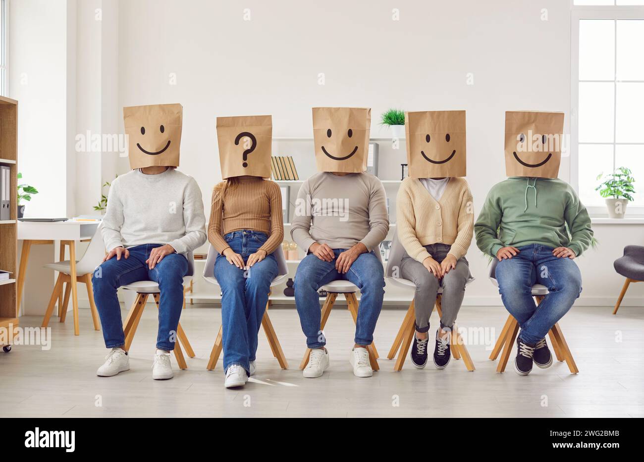 Group of unknown people put paper shopping package bags with emoticons on their heads. Stock Photo