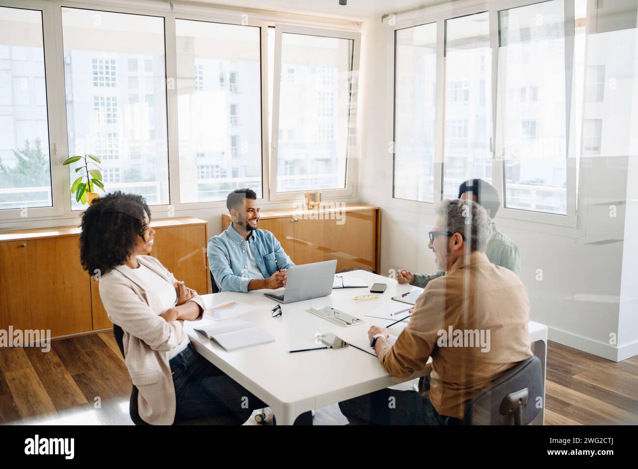 A team of four professionals are gathered around a white table in a ...