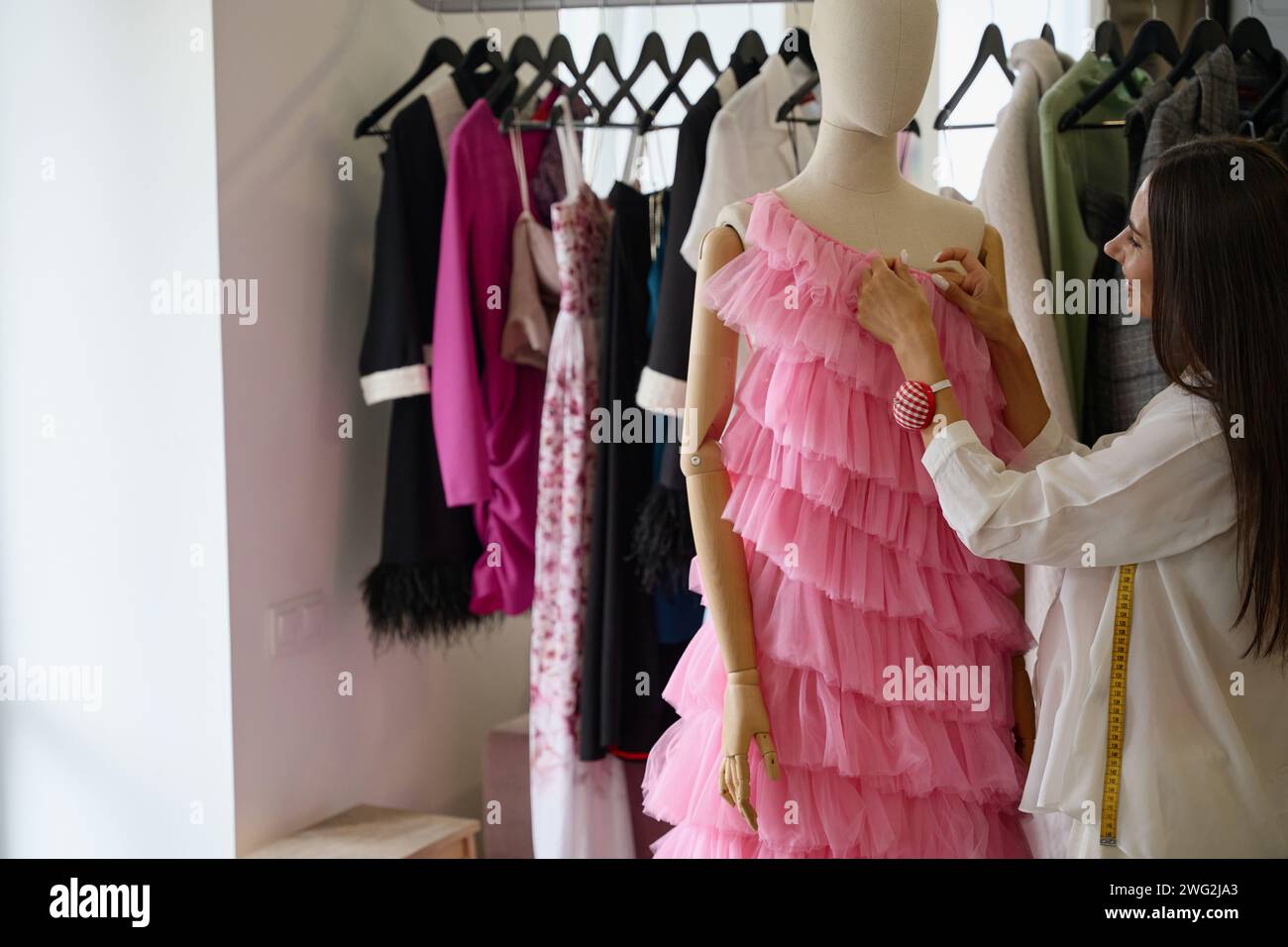 Smiling designer creates a pink evening dress Stock Photo - Alamy