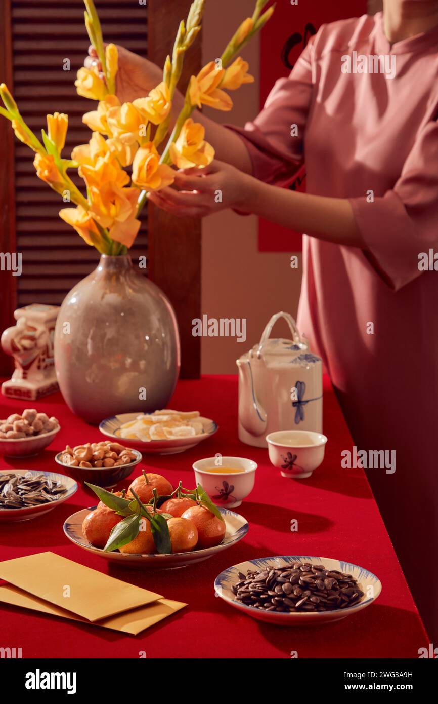 A red-themed table for the Lunar New Year celebration. Tangerines, many kinds of nut, yellow envelopes on the table Stock Photo
