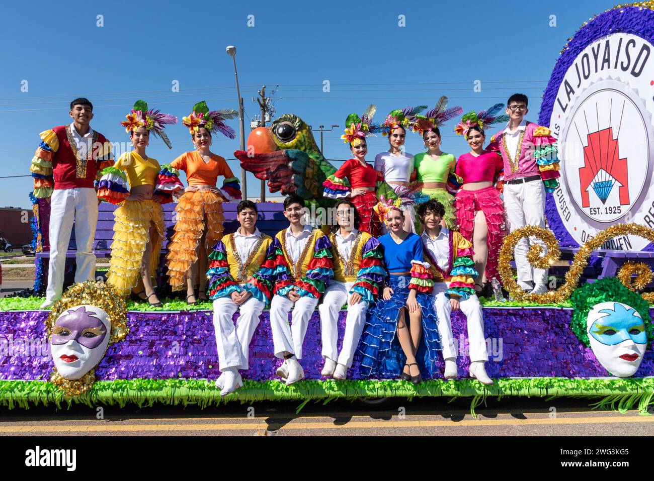 Adults in brightly colored rumba costumes on parade float in the 92nd Annual Texas Citrus Fiesta