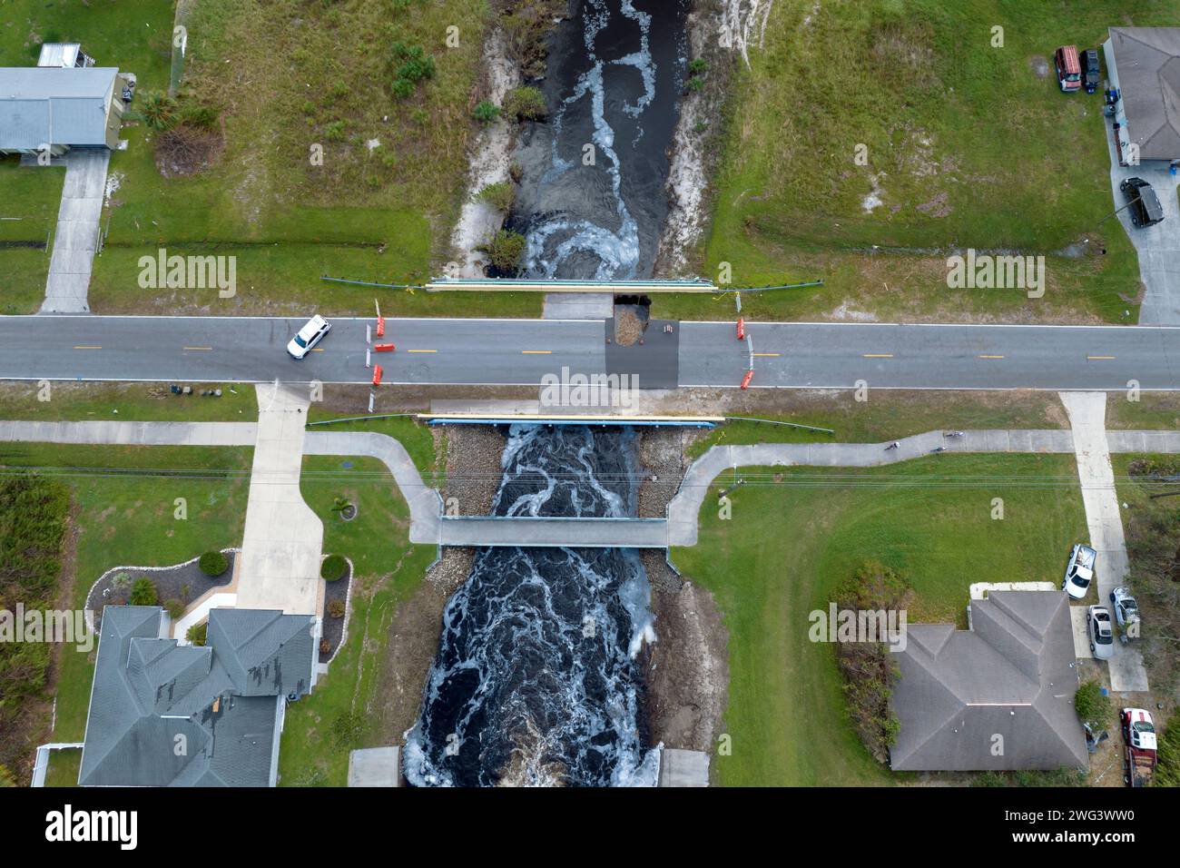 Road construction. Law enforcement police blocking car access at destroyed bridge after hurricane flooding water washed away asphalt in Florida Stock Photo