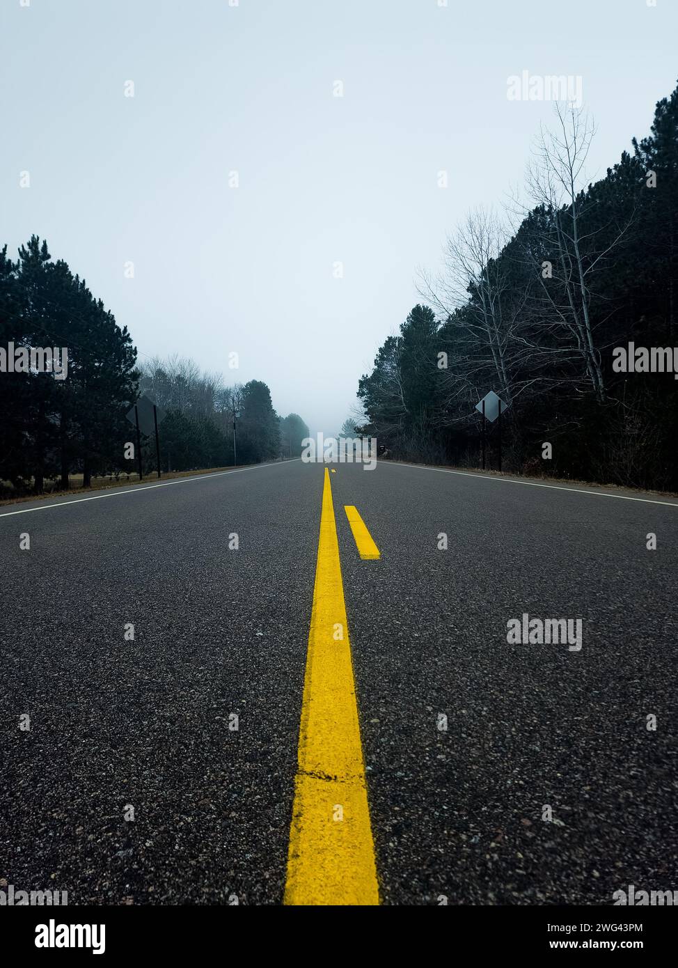 A vibrant yellow line stretches into the distance on a desolate road Stock Photo