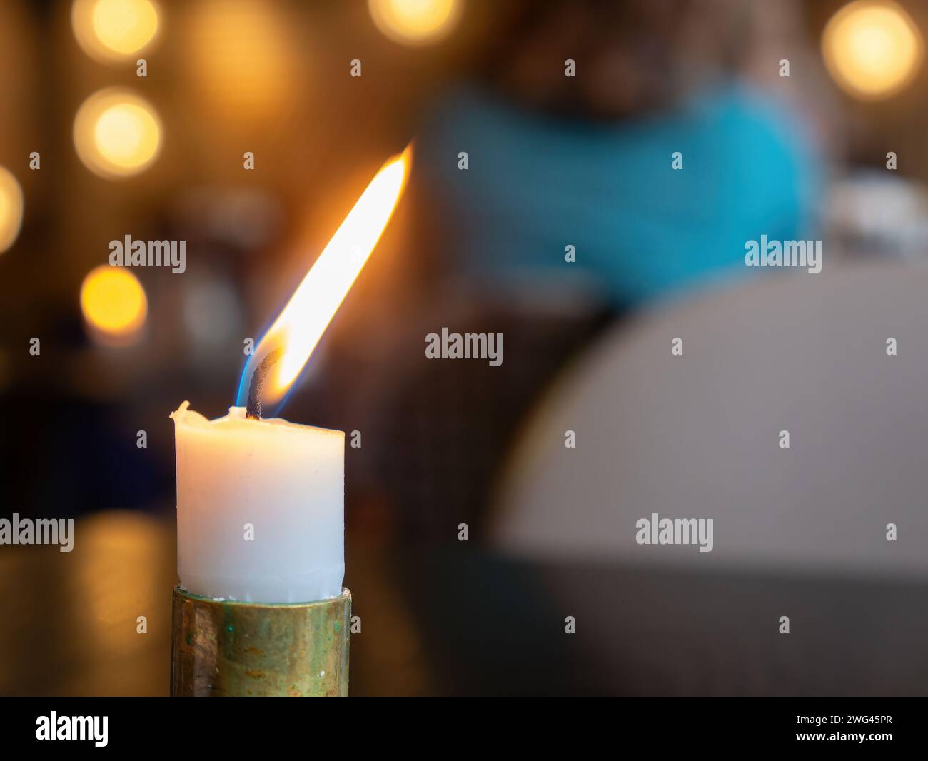 White candle burning. Very shallow depth of field, with only the flame and wick in focus. Stock Photo