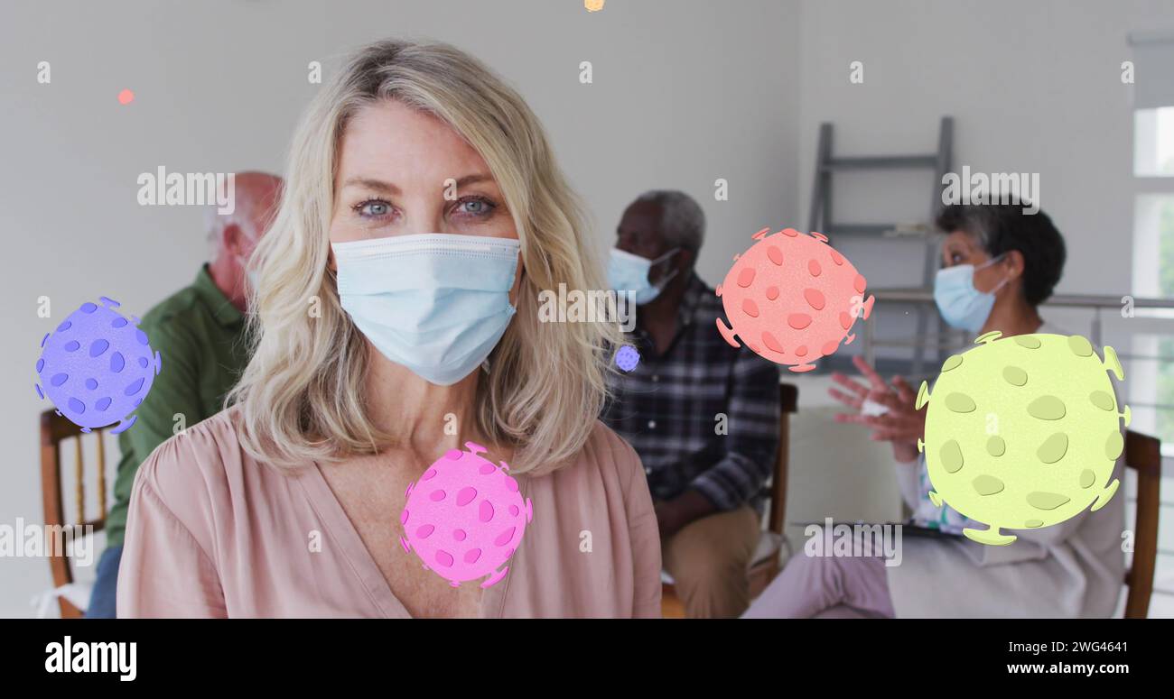 Image of virus cells over diverse group of seniors with face masks Stock Photo