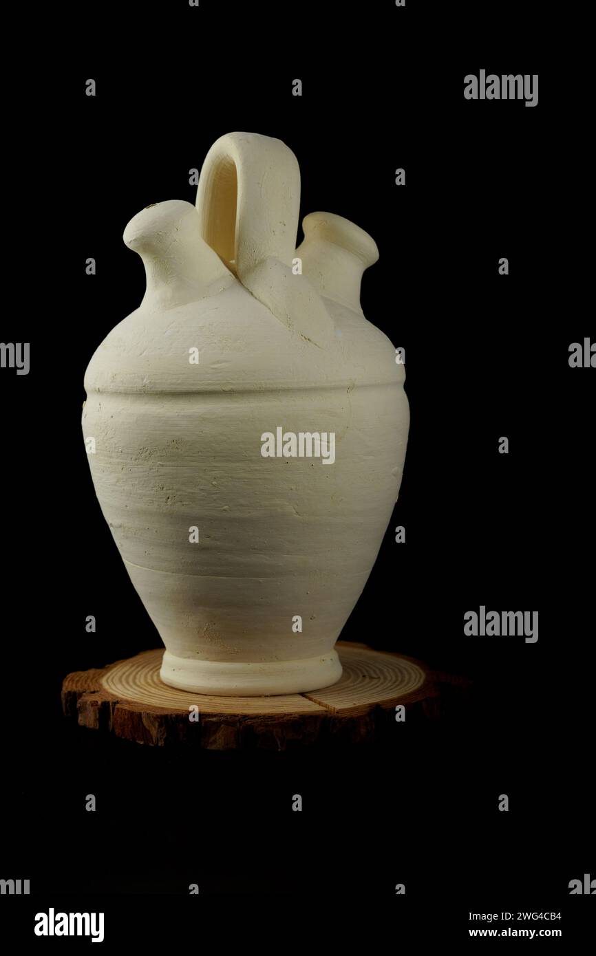 A handmade clay botijo isolated on a black background Stock Photo