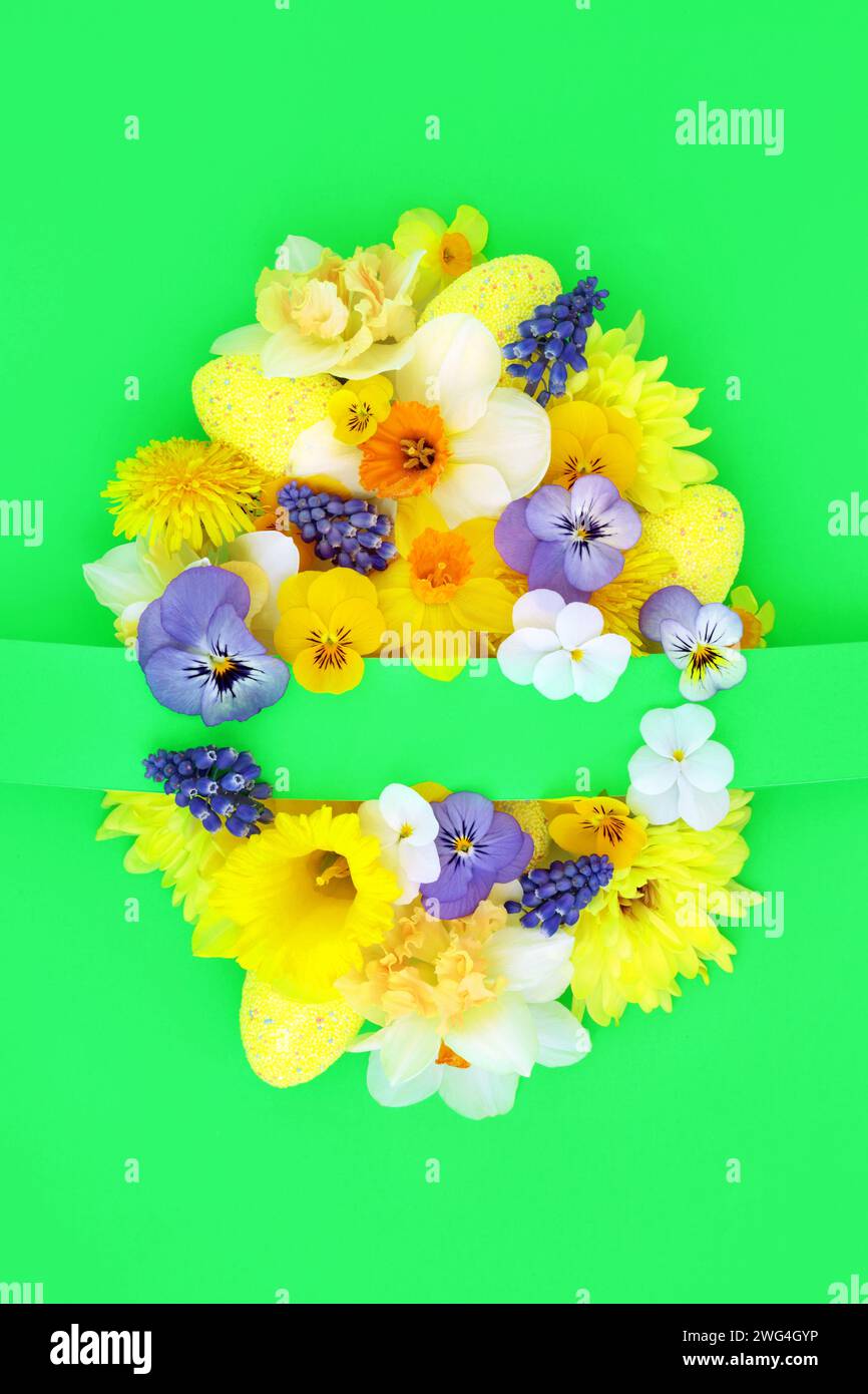 Easter egg concept shape with yellow blue white Spring flowers and decorated eggs on green background. Happy Easter composition for the festive season Stock Photo