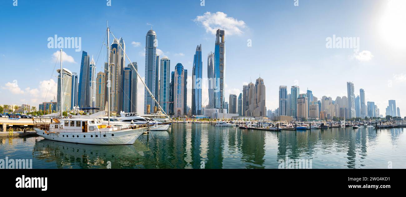 Panoramic view of Dubai marina harbour on a sunny day in the UAE with a bustling metropolis meets serene waters as boats sail beneath a majestic city Stock Photo