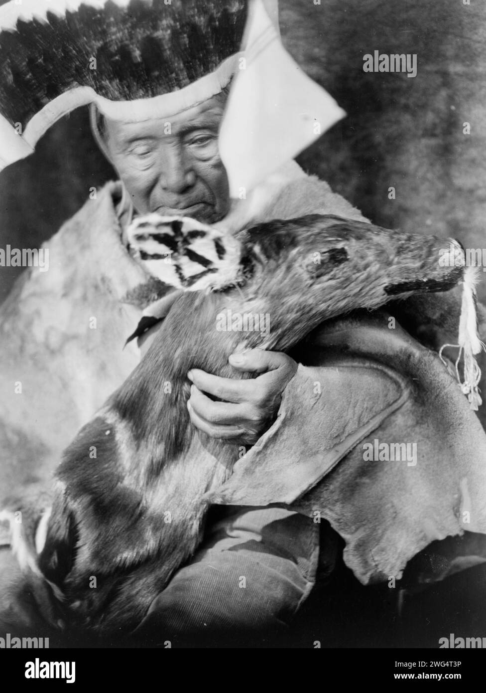 Dancer with black deer effigy-Hupa, c1923. Hupa Indian dancer holding