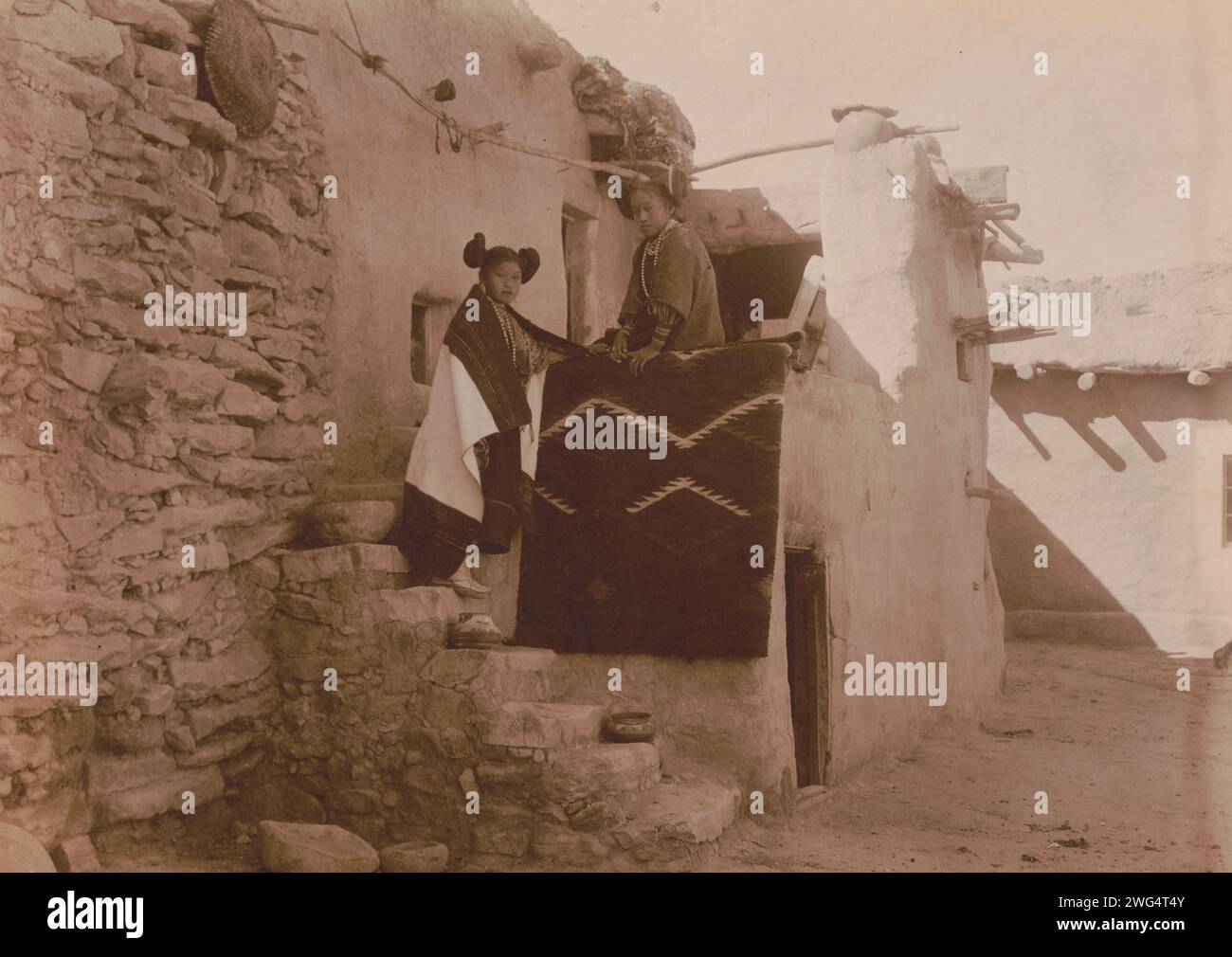 Tewa girls, c1900. Two Tewa girls standing outside pueblo building