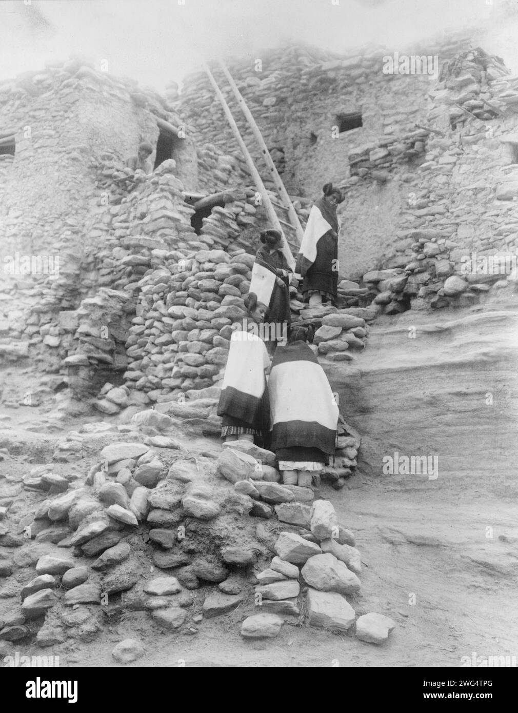 Cliff perched homes-Hopi, c1906. Four Hopi women in front of pueblo buildings. Stock Photo