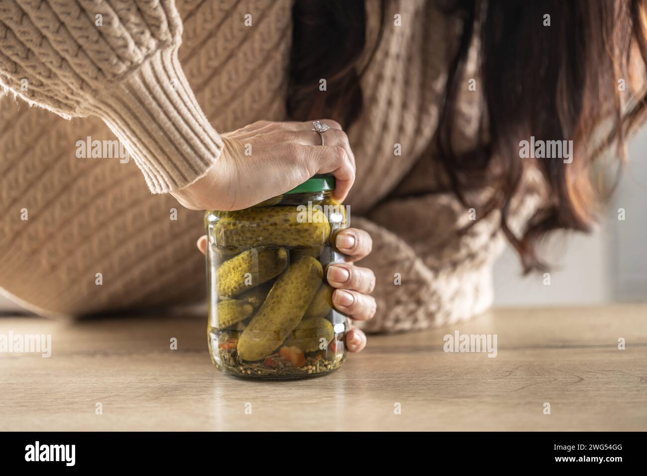 A woman tries to force open a jam jar with cucumbers. Stock Photo