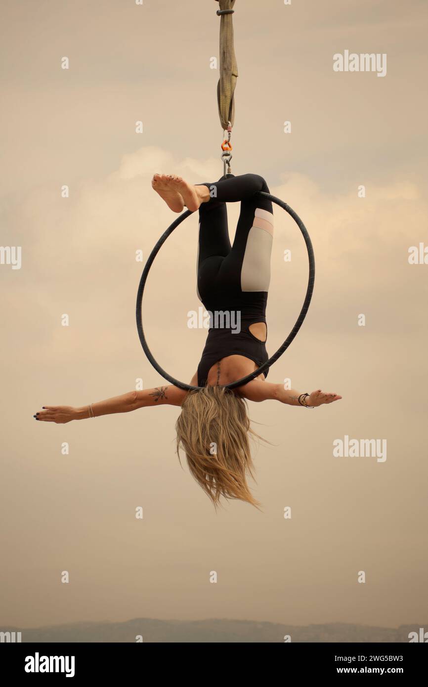 Middle age active woman performing on aerial hoop outdoors Stock Photo