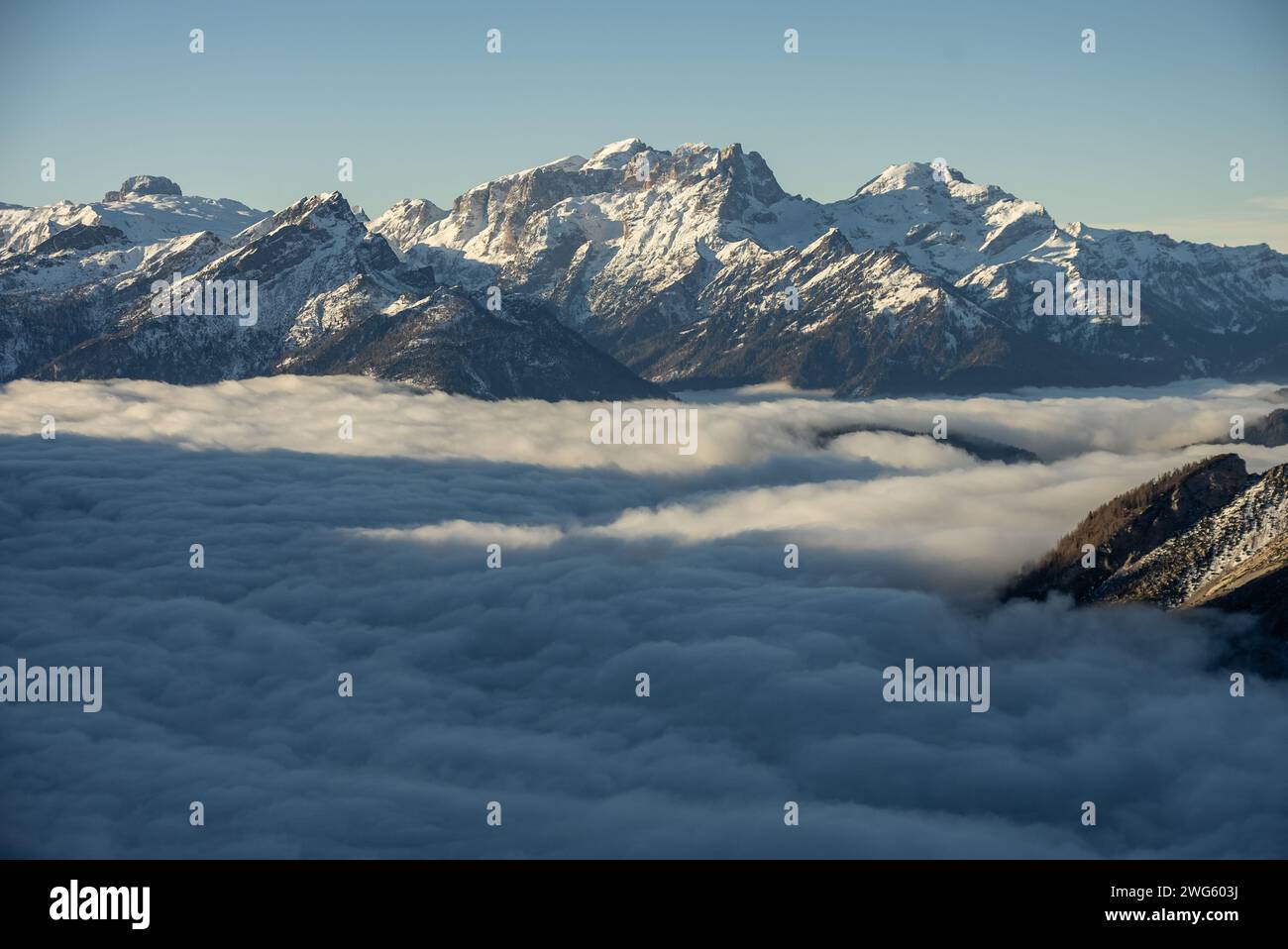 Mountain above clouds. Civetta resort. Panoramic view of the Dolomites mountains in winter, Italy. Ski resort in Dolomites, Italy. Aerial  drone view Stock Photo
