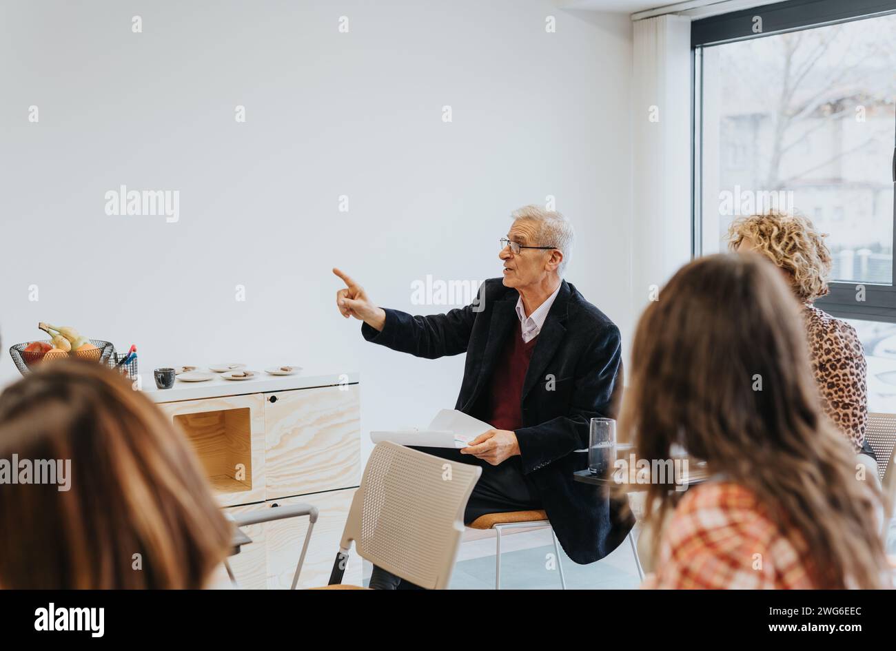 Mature businessman gestures with arm while explaining something during ...