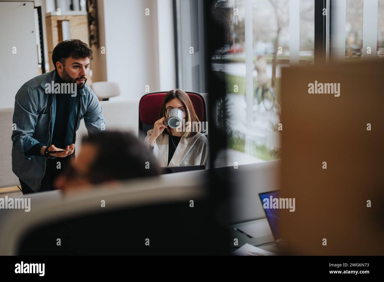 Colleagues engaged in discussion at modern office workspace. Stock Photo