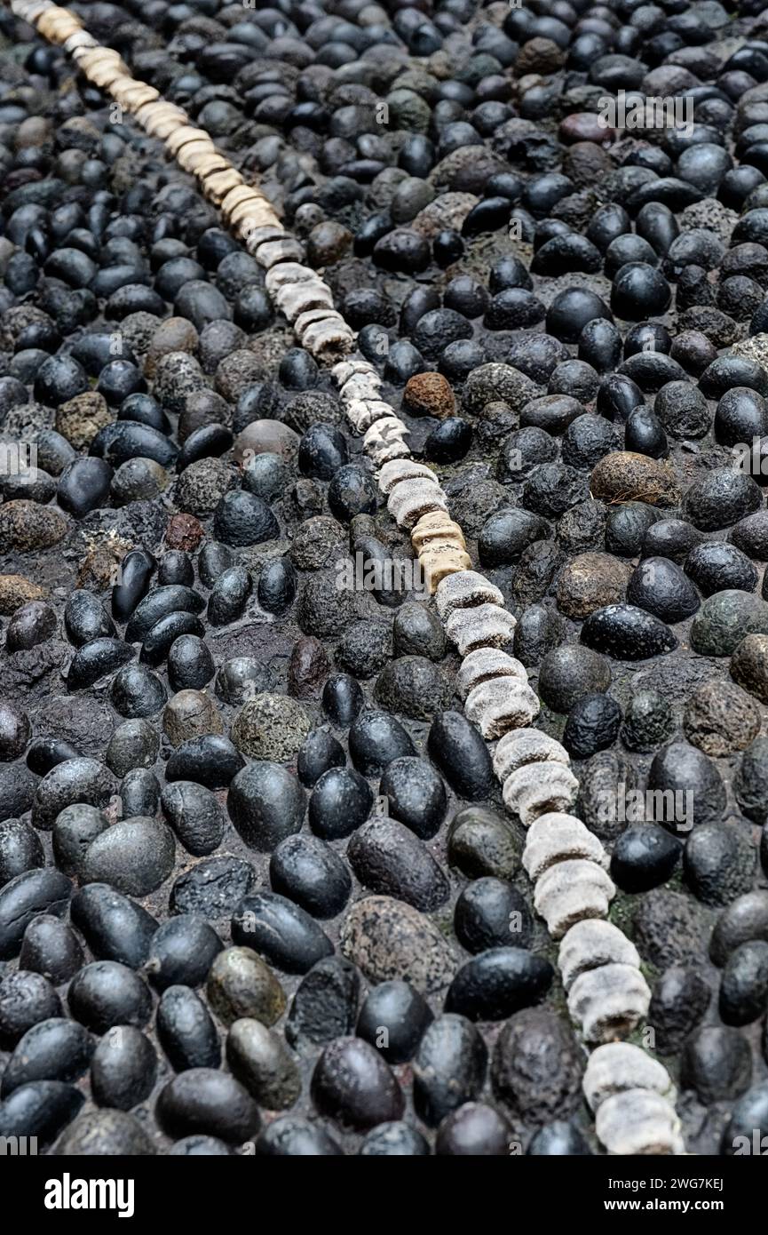 An old courtyard floor in Lima, Peru is covered with stones and a single line of white vertebrae. Stock Photo