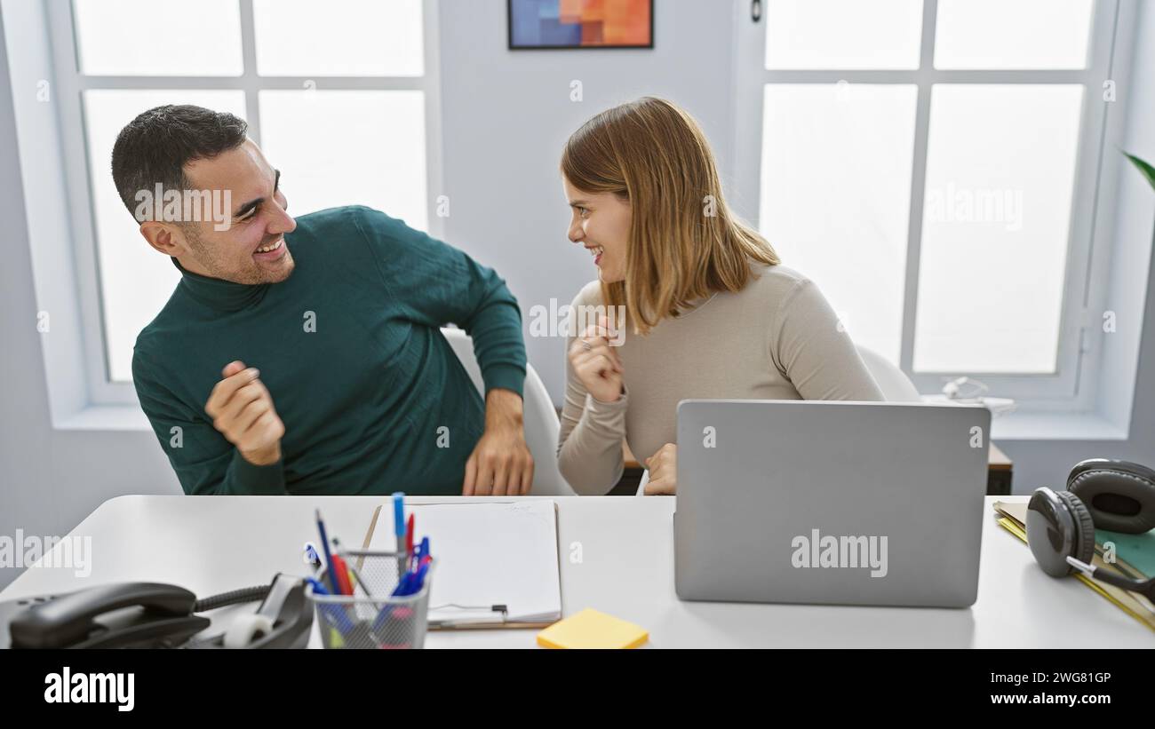 A smiling man and woman engage playfully in a bright modern office(09)