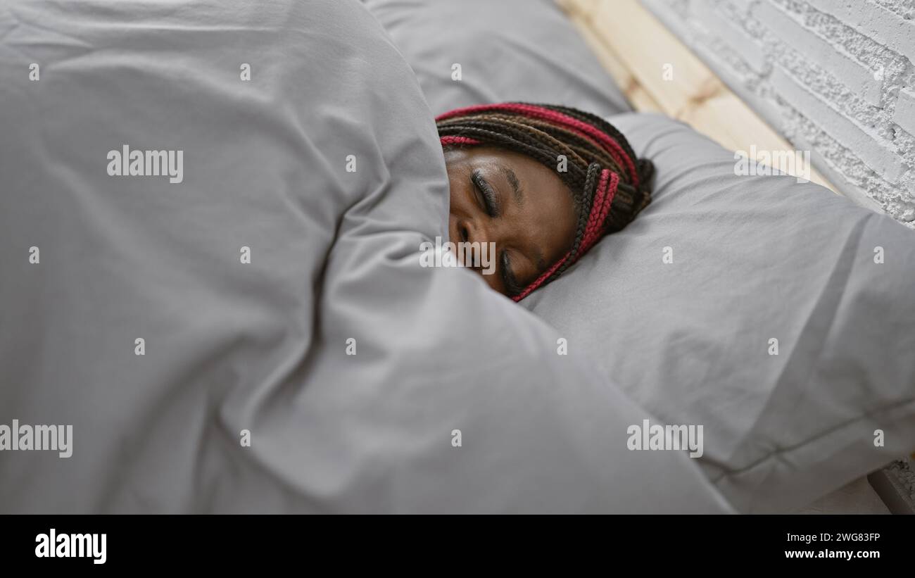 Exhausted african american woman in braids, comfortably lying on a cozy ...